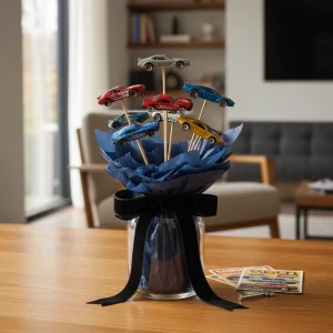 A sophisticated DIY Hot Wheels Bouquet featuring metallic die-cast cars and velvet ribbons arranged on a wooden workspace.